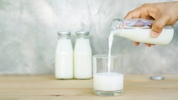 istock man pouring a milk on a wooden table. 819653722