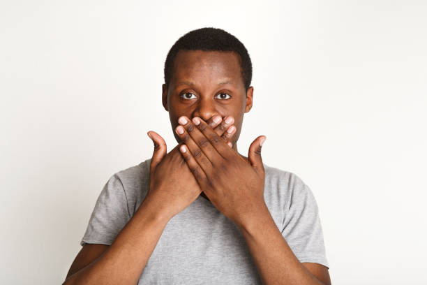 istock Say nothing concept, black man covering mouth with hand 819659422