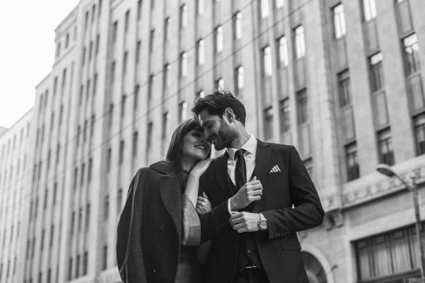 Young and elegant people Two people, man and woman, heterosexual couple, standing on the street, black and white. charming photos stock pictures, royalty-free photos & images