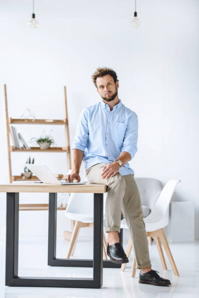istock young businessman sitting on table with laptop in modern office 819662222