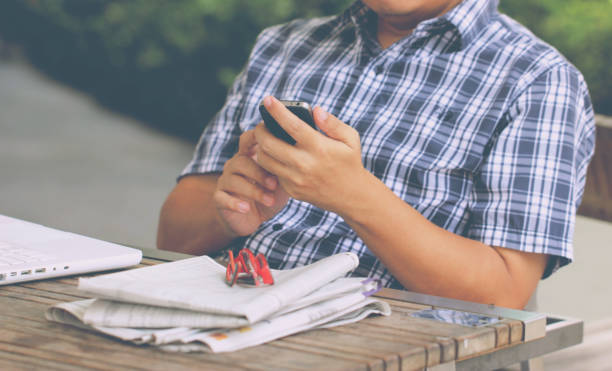 Asian Man's Hand Touching Smart Phone With White Laptop. Asian Man's Hand Touching Smart Phone With White Laptop. newpapers stock pictures, royalty-free photos & images