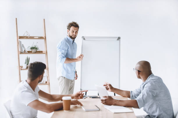 istock young businessman at white board making presentation to colleagues 819662416