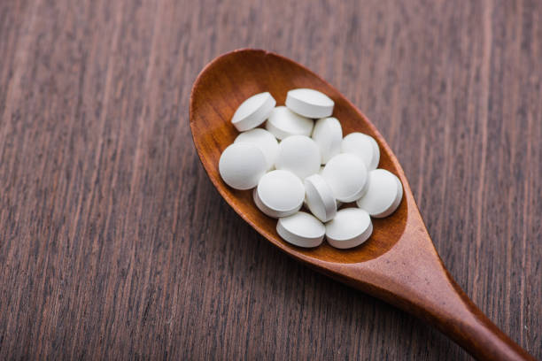 istock white medical pills on wooden spoon 819665538