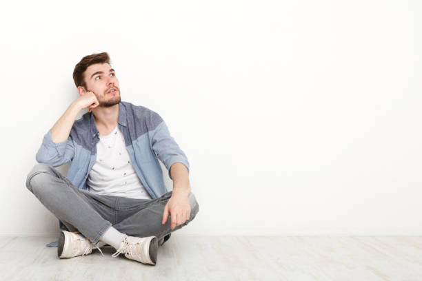 istock Pensive man sitting on floor and looking upwards 819665958