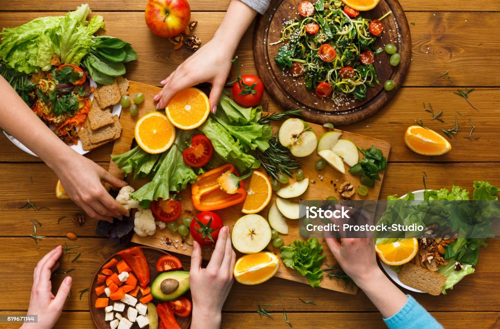 Dinner table, women eat healthy food at home kitchen Healthy food dinner table. Women at home together, eating fruits and vegetables, top view, flat lay, crop Healthy Eating Stock Photo