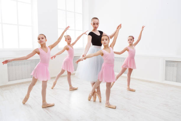 insegnante che aiuta i suoi studenti durante la lezione di danza - scuola di danza classica foto e immagini stock