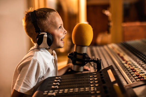 istock Happy little boy talking on a microphone in a radio station. 819695086