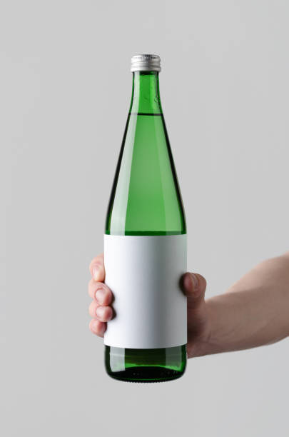 Water Bottle Mock-Up. Blank Label - Male hands holding a water bottle on a gray background