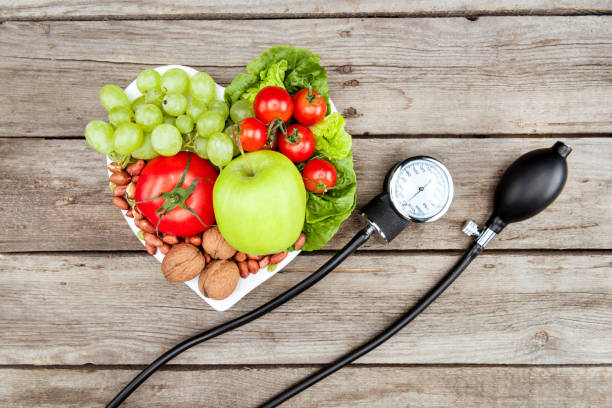 top view of fresh various vegetables, fruits and blood pressure gauge on wooden surface, healthy eating concept - vegan food still life horizontal image imagens e fotografias de stock