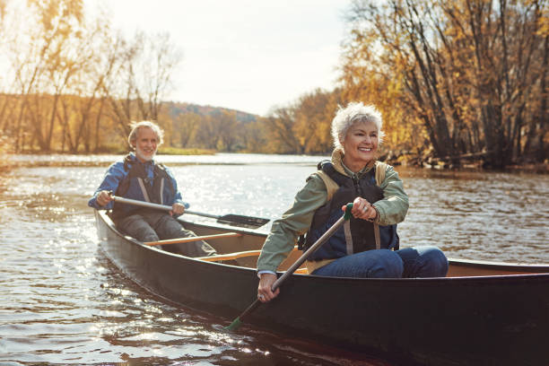 remare verso una pensione rilassante - canoeing canoe senior adult couple foto e immagini stock