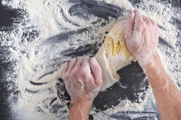 istock Hands top view knead dough on black background 819734000