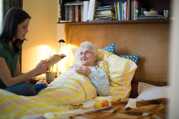 pracownik socjalny odwiedza starszą kobietę w domu - grandparent family reading inside of zdjęcia i obrazy z banku zdjęć