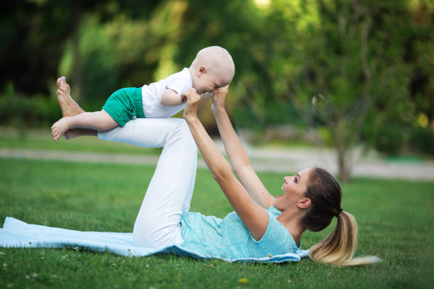 Sportive happy mother is doing workout on lawn with little son. Sports concept, summer time stock photo