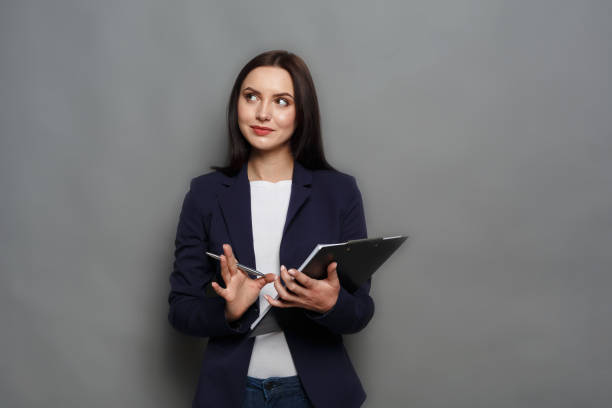 istock Confident woman with notepad on gray background 819748252