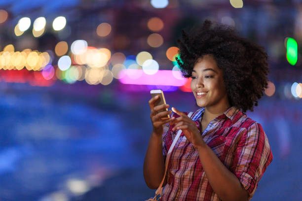 istock Smiling tourist using smart phone at night on street 819770834