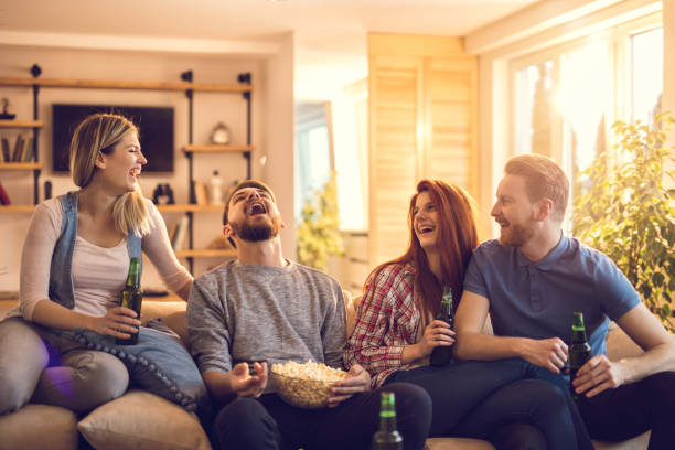 istock Playful man catching popcorn with his mouth while his friends are watching. 819775754