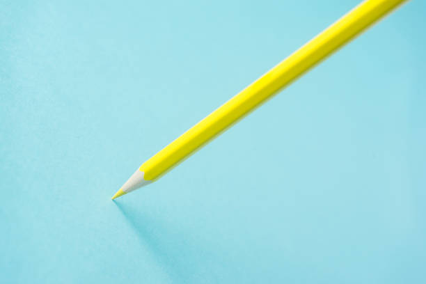 istock ne yellow color pencil stand on blue paper background 819776238