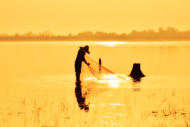 istock Fishing man in silhouette on gold sunset background. 819798394