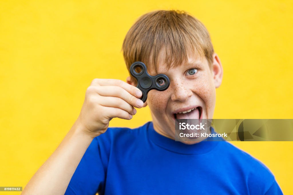 Muchacho con spinner fidget sobre fondo amarillo. - Foto de stock de A la moda libre de derechos