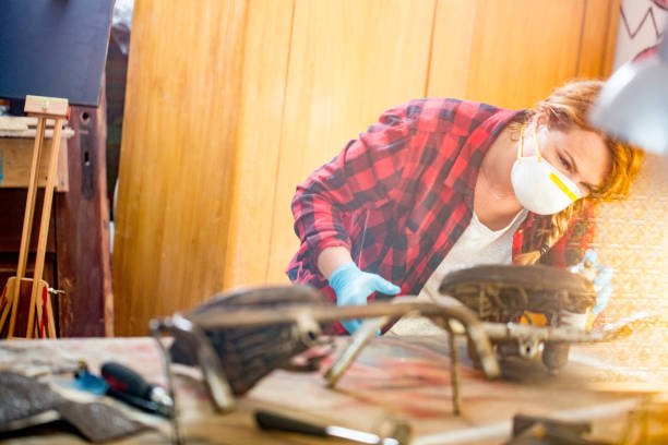istock Young Restorer Woman Wearing a Protection Mask while Spraying Antiques 819829306