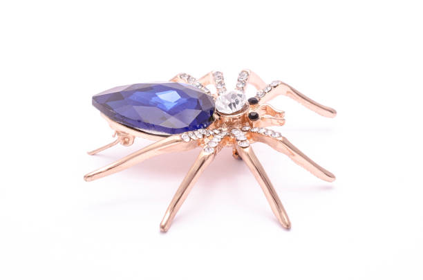 istock Golden spider with a big blue stone isolated on white 819833204