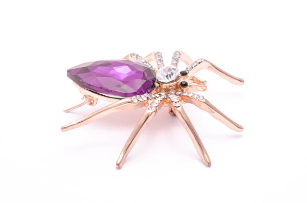 istock Golden spider with a big purple stone isolated on white 819833218