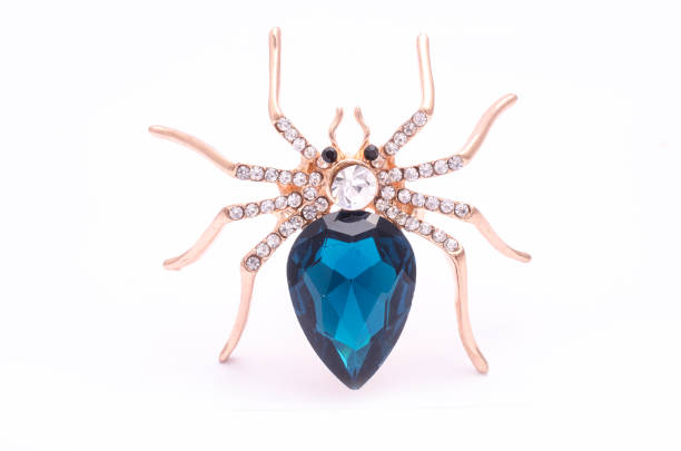 istock Golden spider with a big blue stone isolated on white 819833230