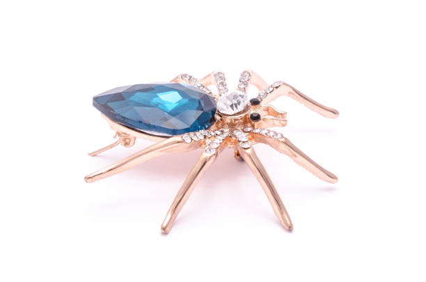 istock Golden spider with a big blue stone isolated on white 819833444
