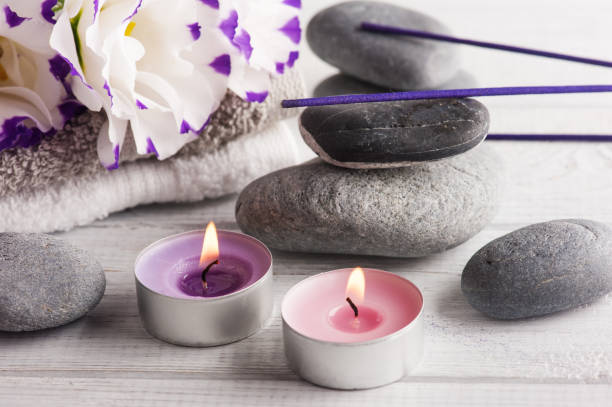 istock Spa composition with towels, lit candles, purple aroma sticks 819835288