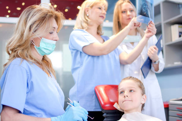 Scared girl patient with dentist, assistant and nurse in a dental office. Scared girl patient with dentist, assistant and nurse in a dental office. Dental Hygienist Schools stock pictures, royalty-free photos & images