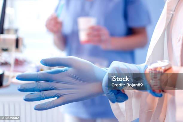 Nahaufnahme Des Weiblichen Arzt Hände Aufsetzen Blau Sterilen Ophandschuhen In Der Medizinischen Klinik Stockfoto und mehr Bilder von Handschuh