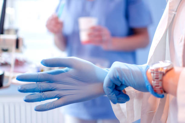 cerca de las manos de la doctora ponerse guantes quirúrgicos esterilizados azul en la clínica médica. - dental hygiene fotografías e imágenes de stock