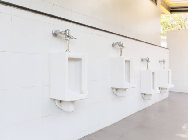 Urinal Tile Wall Row of white urinal for men on tile wall in toilet. flushing valve public restroom toilet stock pictures, royalty-free photos & images