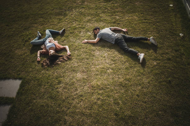 High angle view of young exhausted couple lying on the grass apart from each other. Copy space.
