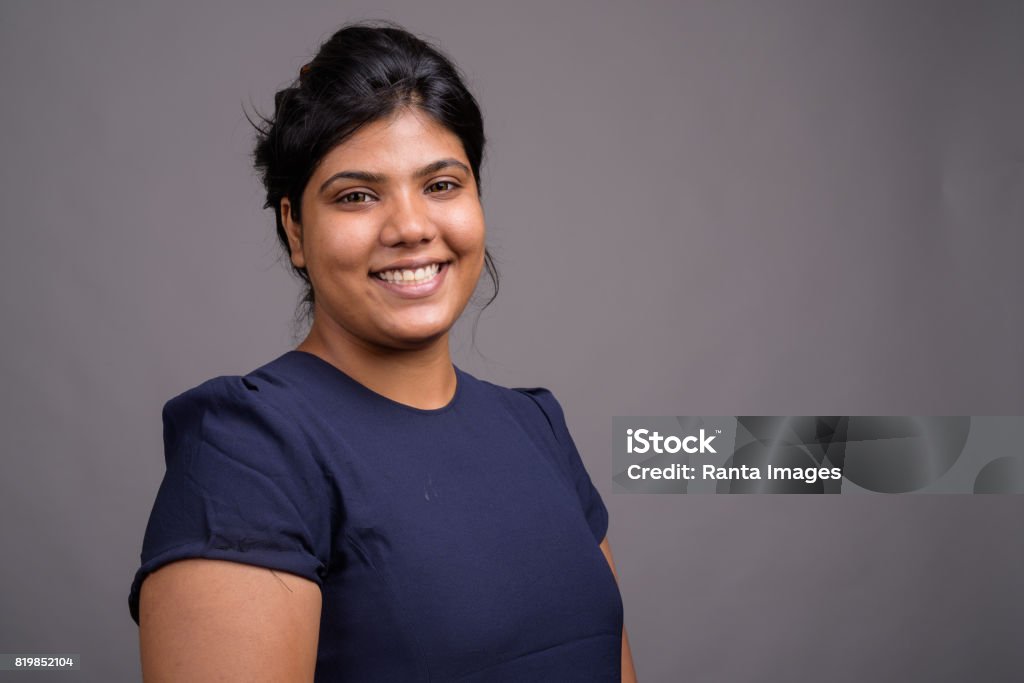 Studio shot of young overweight beautiful Indian woman against gray background Studio shot of young overweight beautiful Indian woman against gray background horizontal shot One Woman Only Stock Photo
