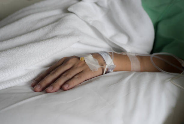istock Hand and arm with saline solution tube on hospital bed. 819856846