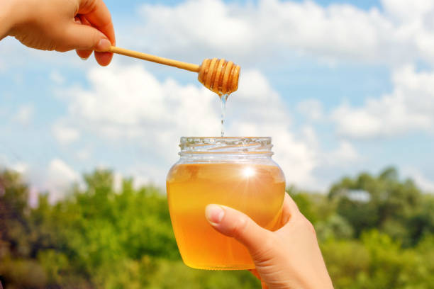 istock Glass honey pot in hands. 819856928