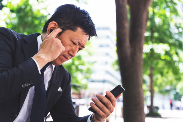 istock Serious expression on a businessman as he attempts to focus on a video conferencing application on his smart phone 819878572