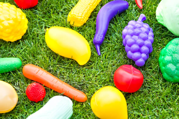 Plastic toy fruits and vegetables on green fresh grass