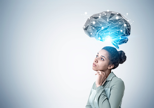 Side view of a pensive African American woman standing near a gray wall with a black brain hologram shining with a blue light. Mock up
