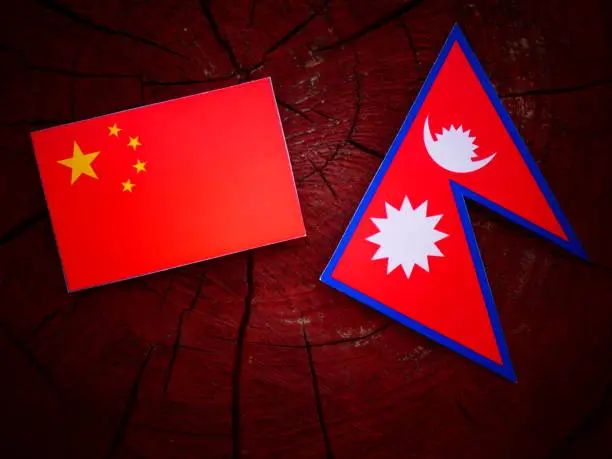 Chinese flag with Nepali flag on a tree stump isolated