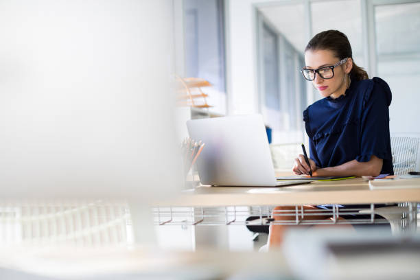 istock Female executive working over laptop and graphic tablet at her desk 819946474