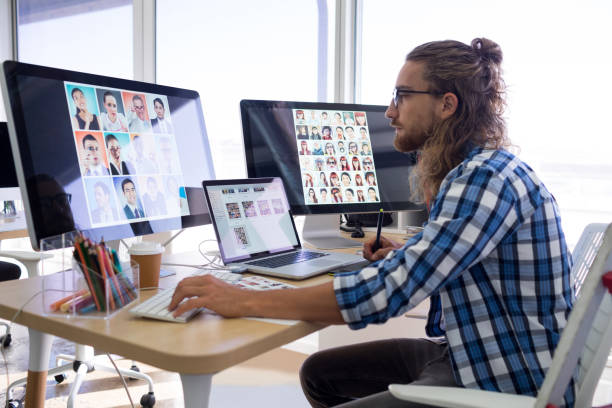Male executive working over laptop and graphic tablet at his desk