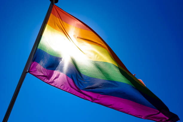 istock Rainbow flag waiving in the wind with sun shining through it 819953326