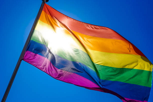 istock Rainbow flag waiving in the wind with sun shining through it 819953388