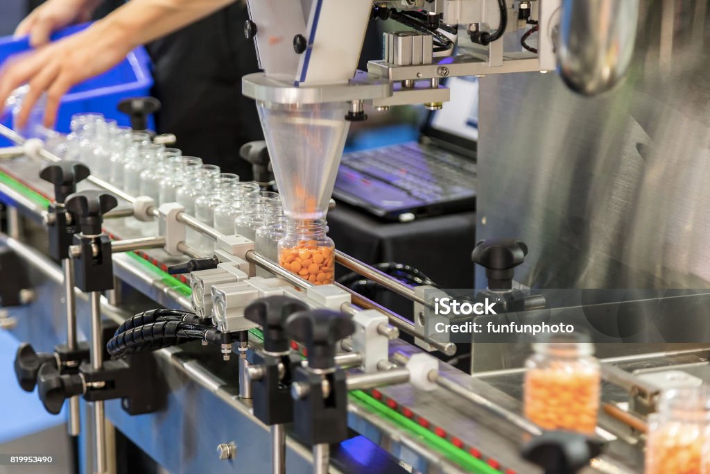 Tablet / Capsule counting machine conveyor in production line of pharmaceutical industry. Manufacturing Stock Photo