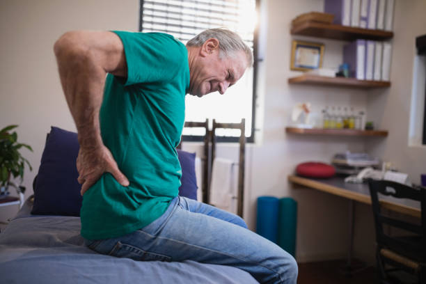 istock Side view of male patient grimacing from back ache while sitting on bed 819965232