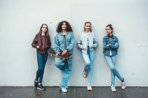 group of four cool teenage girls outdoors in city, looking to camera