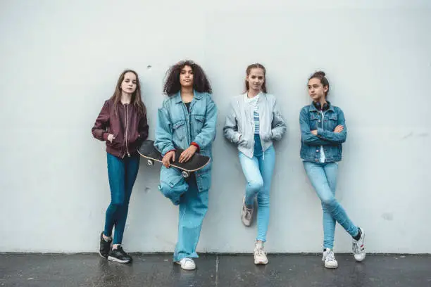 Photo of four teenage girls standing in front of concrete wall