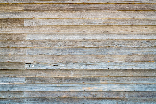 background and texture of  an old, weathered wood siding of abandoned farm house
